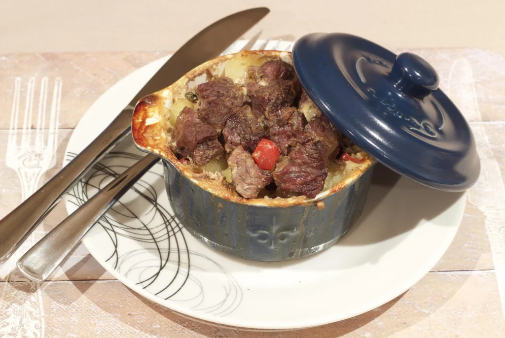 A rustic pot of beef stew with tender chunks of meat and vegetables on a wooden table